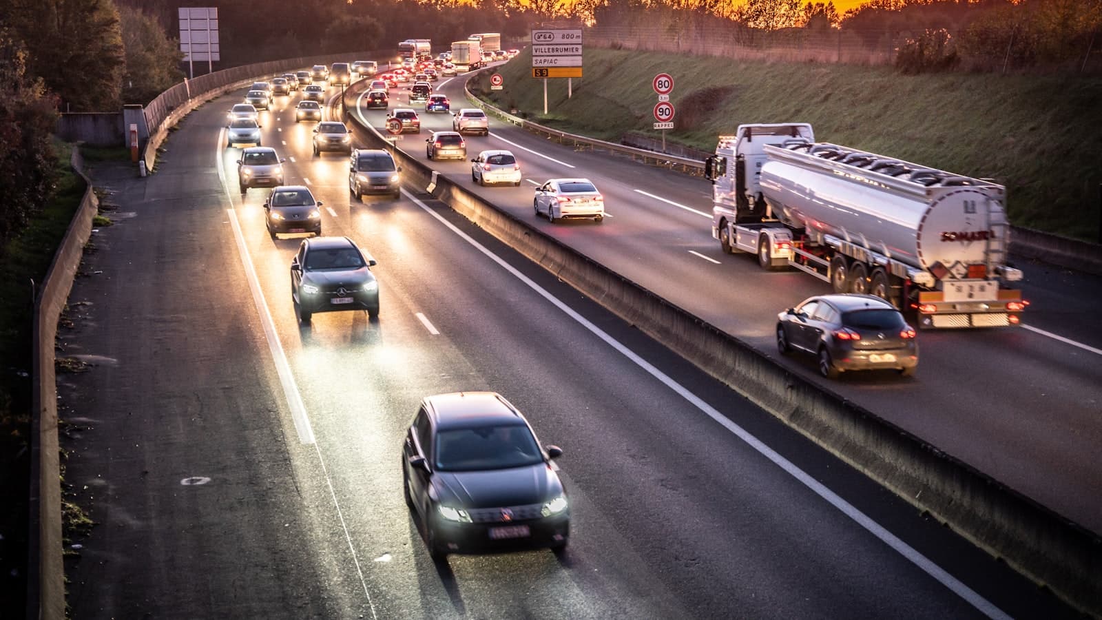 Une autoroute à plusieurs voies remplie de circulation, photographiée au coucher du soleil.