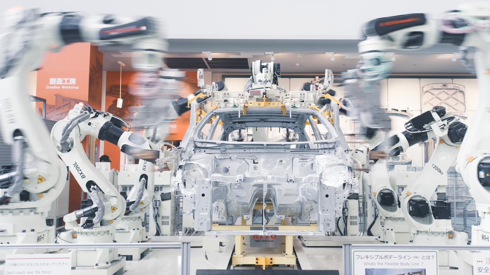 Bras robotisés assemblant une caisse de voiture sur une ligne de production.