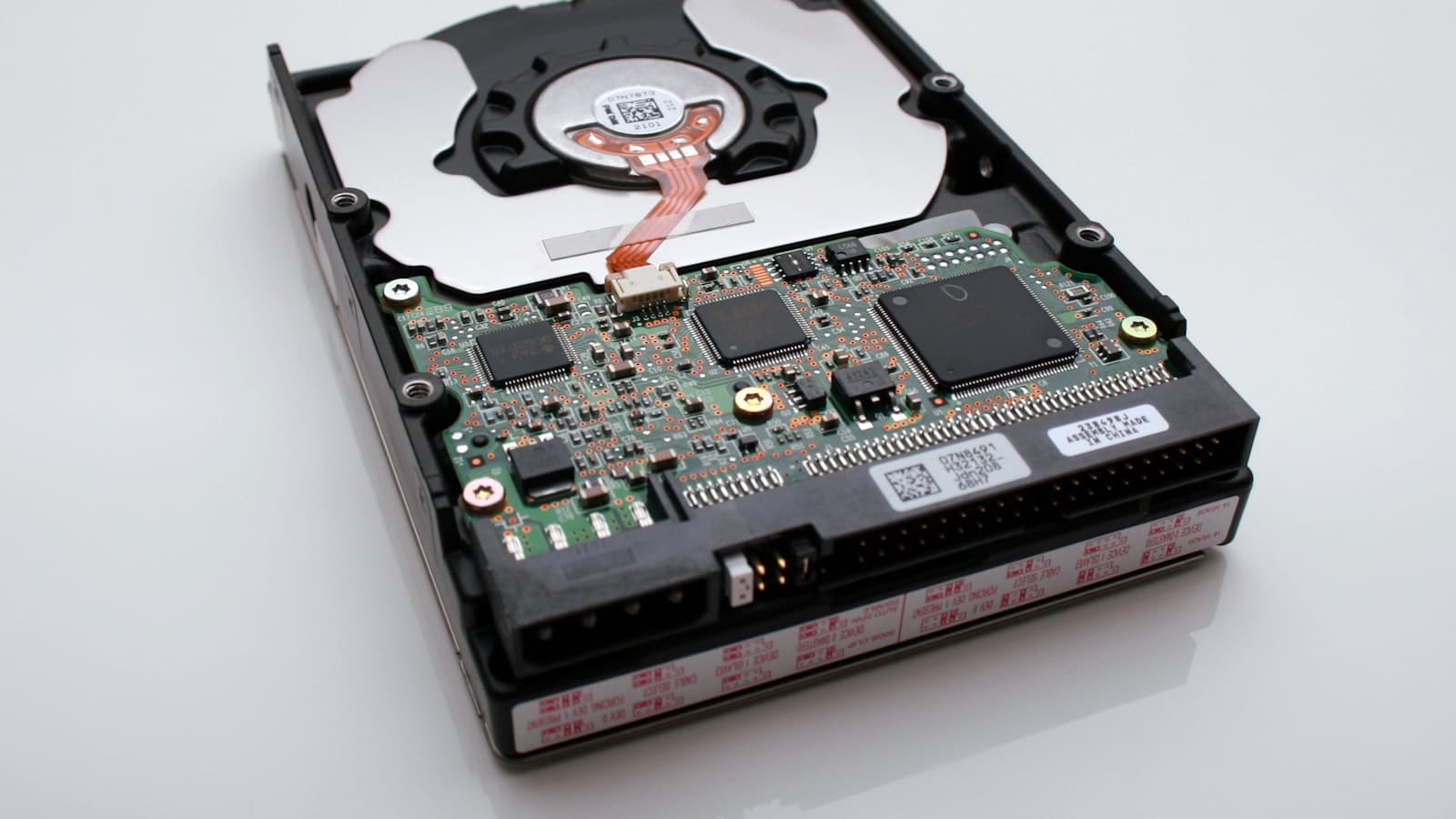 Un disque dur interne ouvert, plateau et bras de lecture visibles.