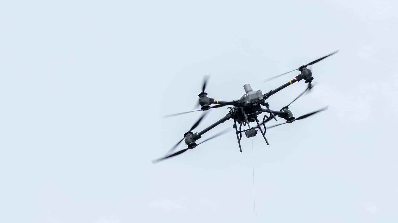 Un drone en vol devant un ciel nuageux.