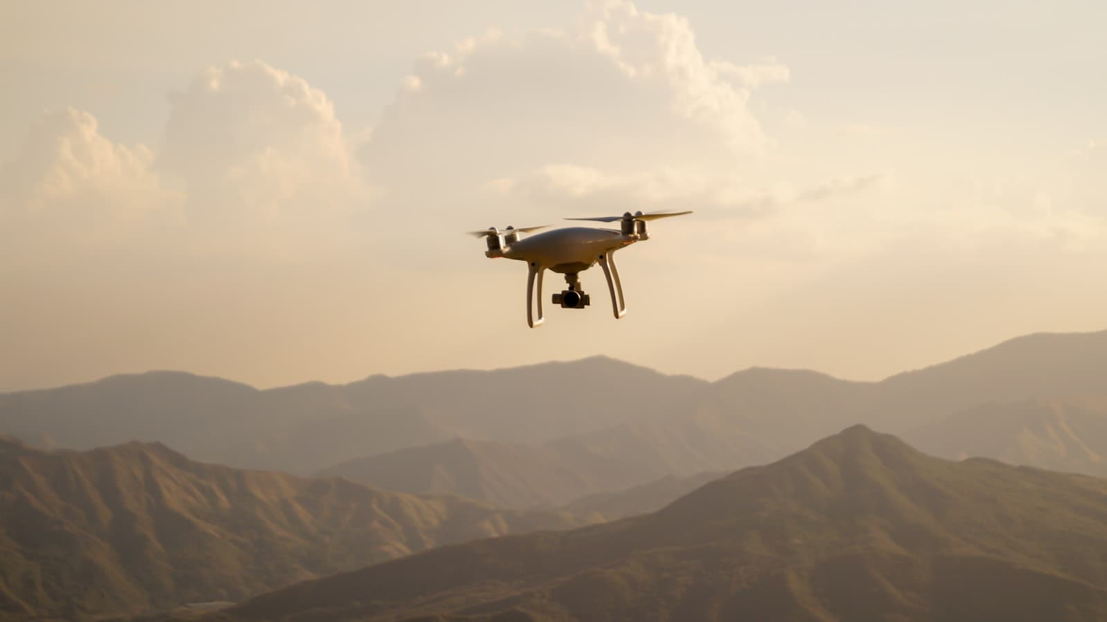 Un drone noir en vol au-dessus de montagnes.