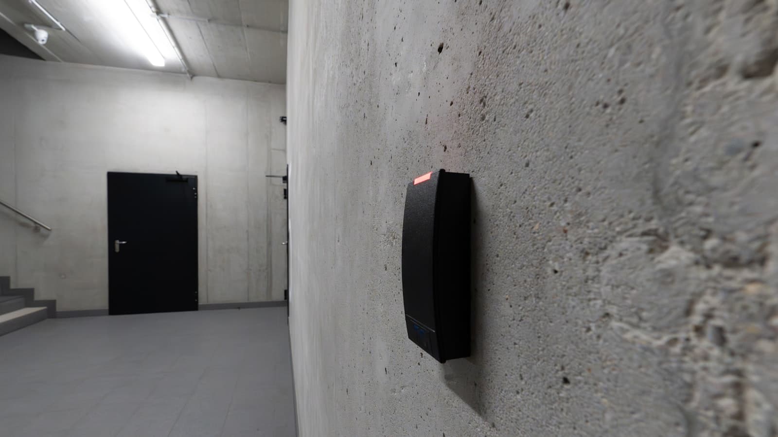 Un lecteur de badge fixé près d'une porte sombre.