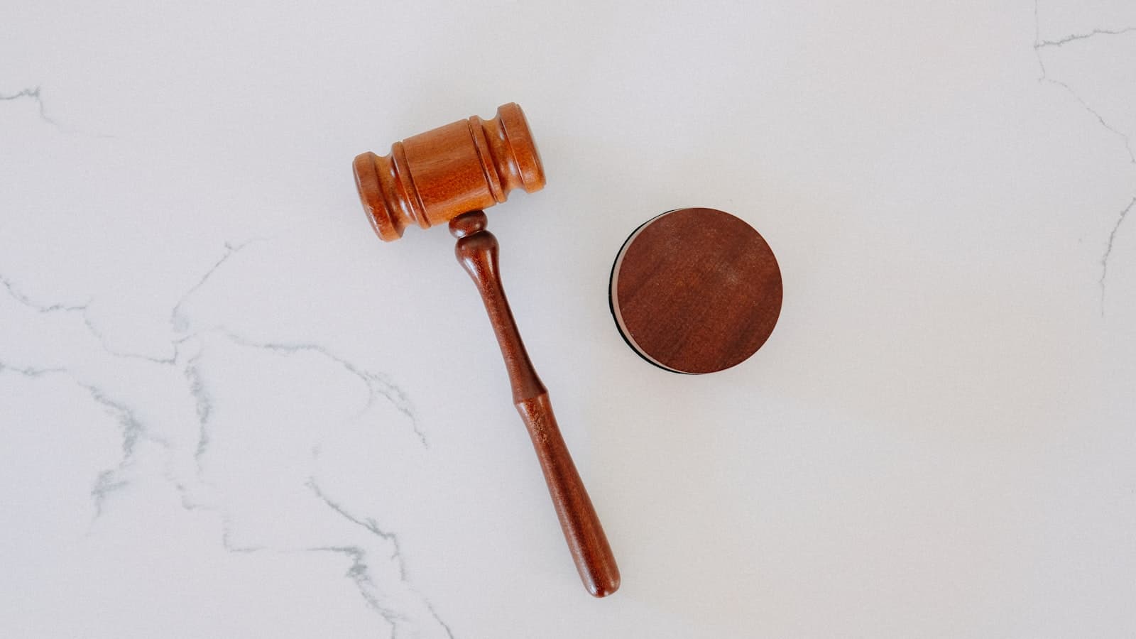 Un marteau de juge en bois posé sur son socle, sur une surface de marbre.