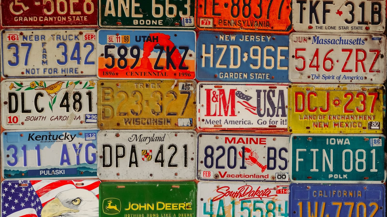 Un mur couvert de plaques d'immatriculation de différentes couleurs.