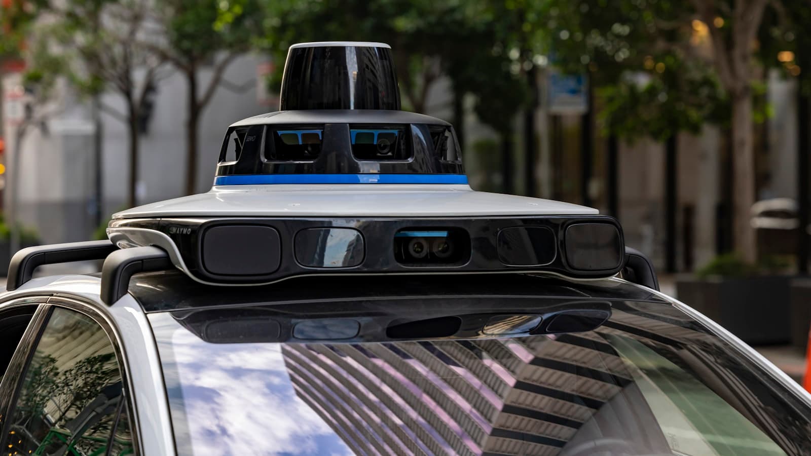 Une voiture autonome équipée de capteurs sur le toit, dans une rue urbaine.