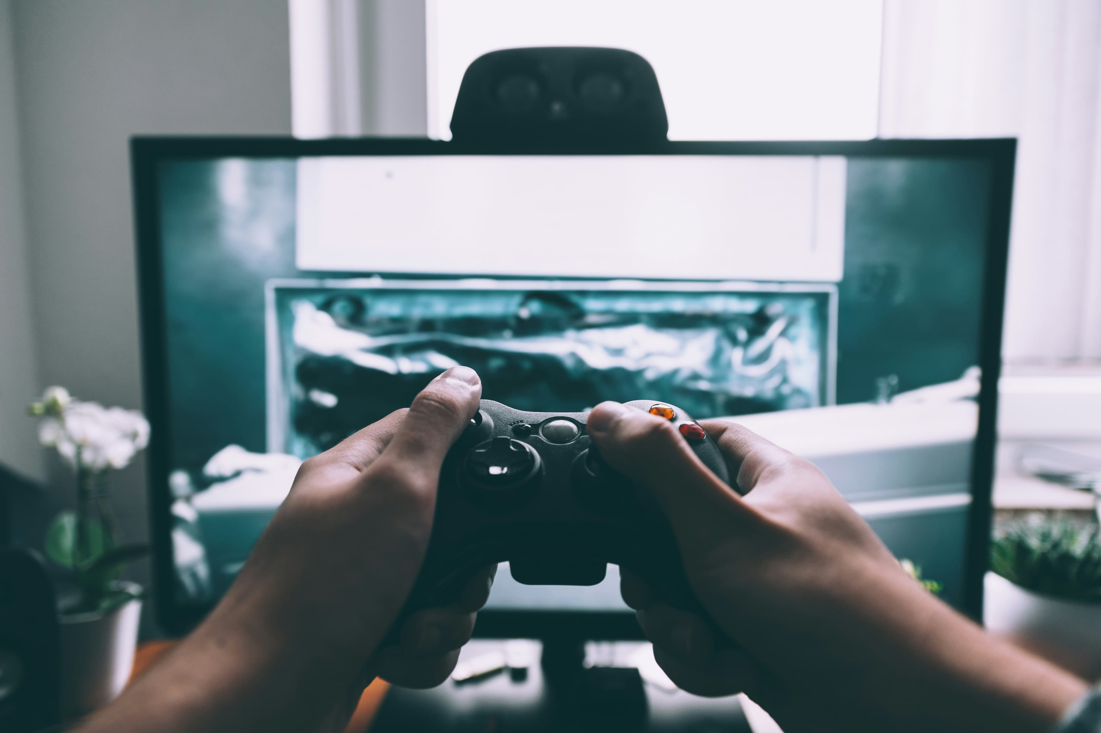 Personne tenant une manette de jeu vidéo face à un téléviseur