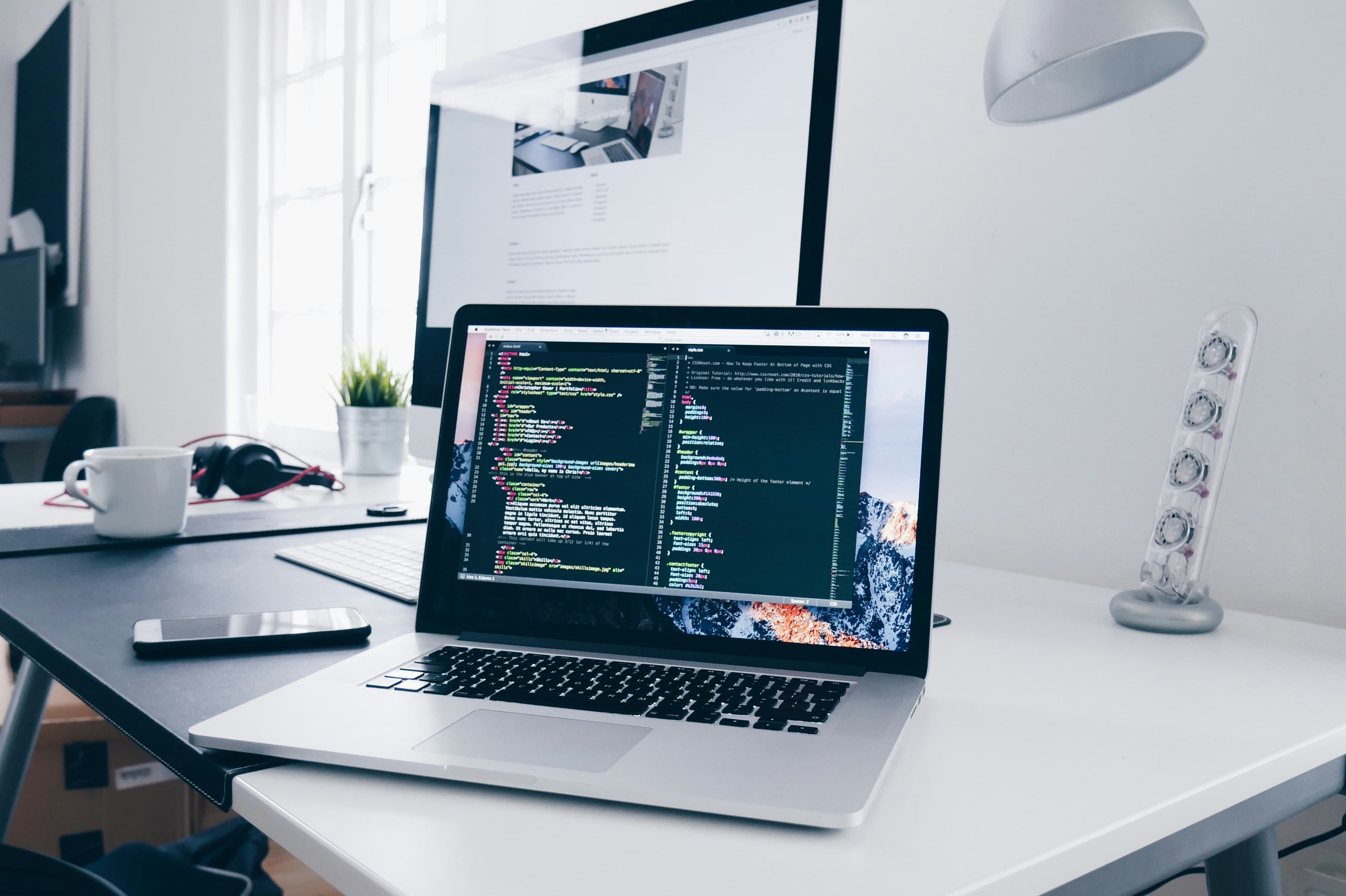 Ordinateur portable ouvert sur un bureau blanc, affichant du code sur son écran