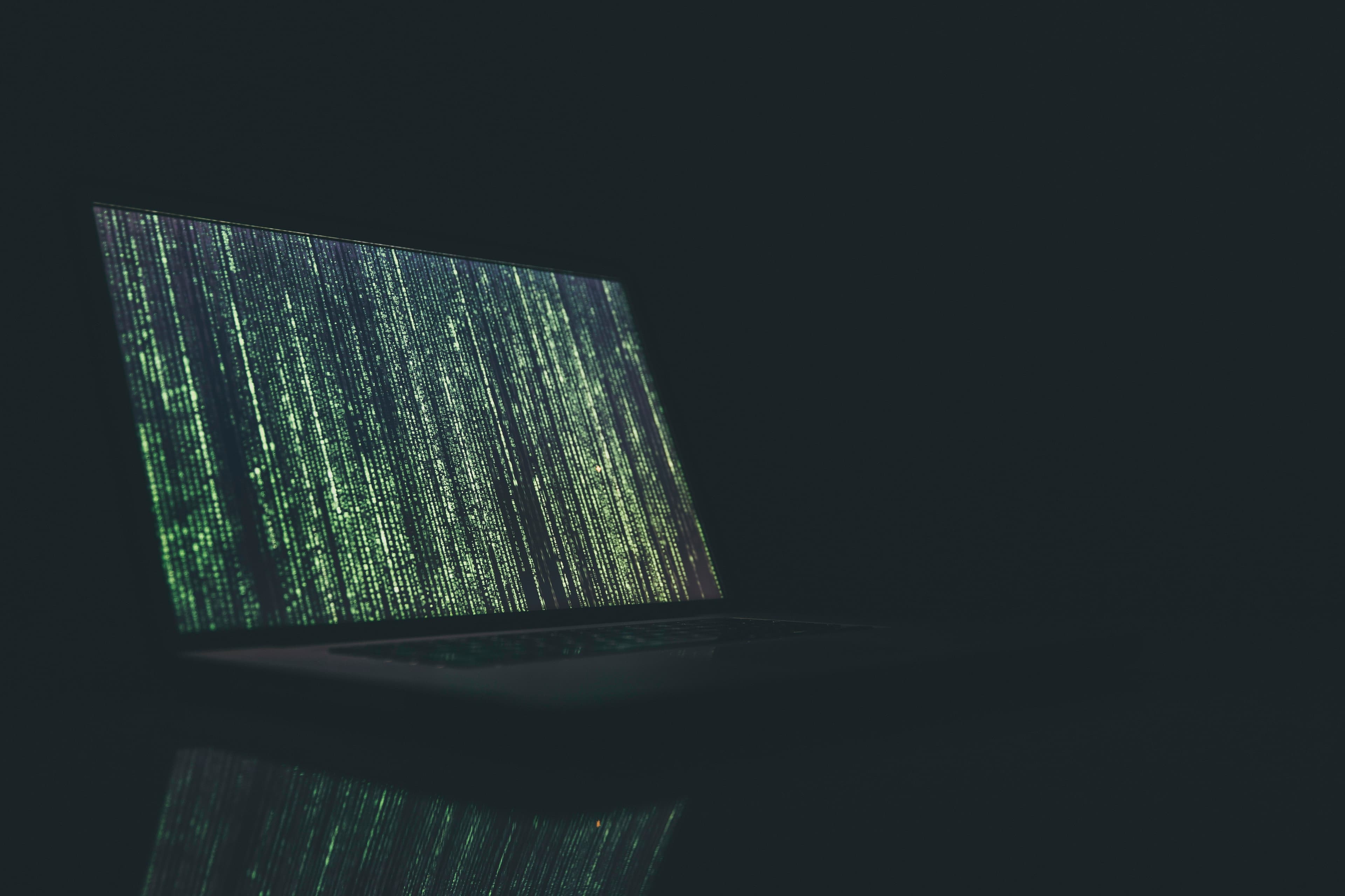 Ordinateur portable ouvert affichant du code à l'écran dans une pièce sombre