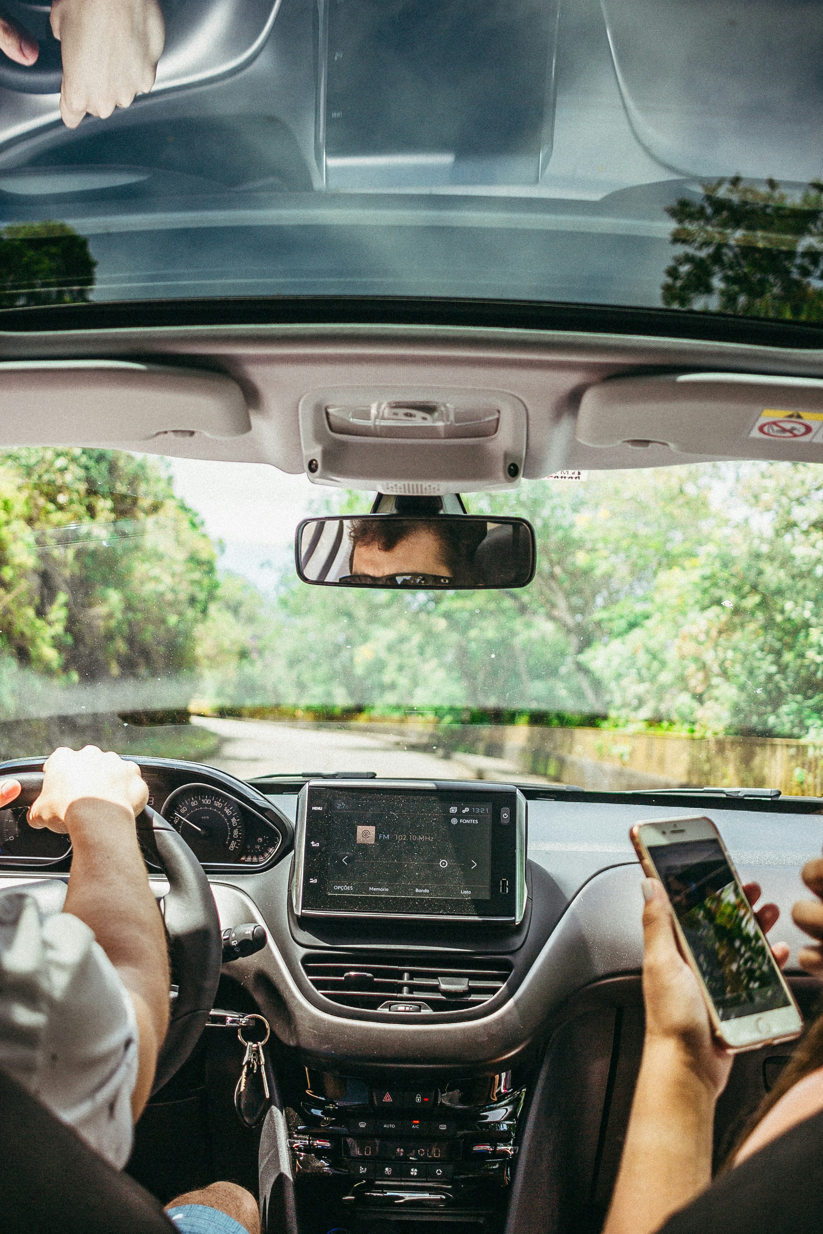 Homme assis dans une voiture tenant son téléphone à côté du conducteur