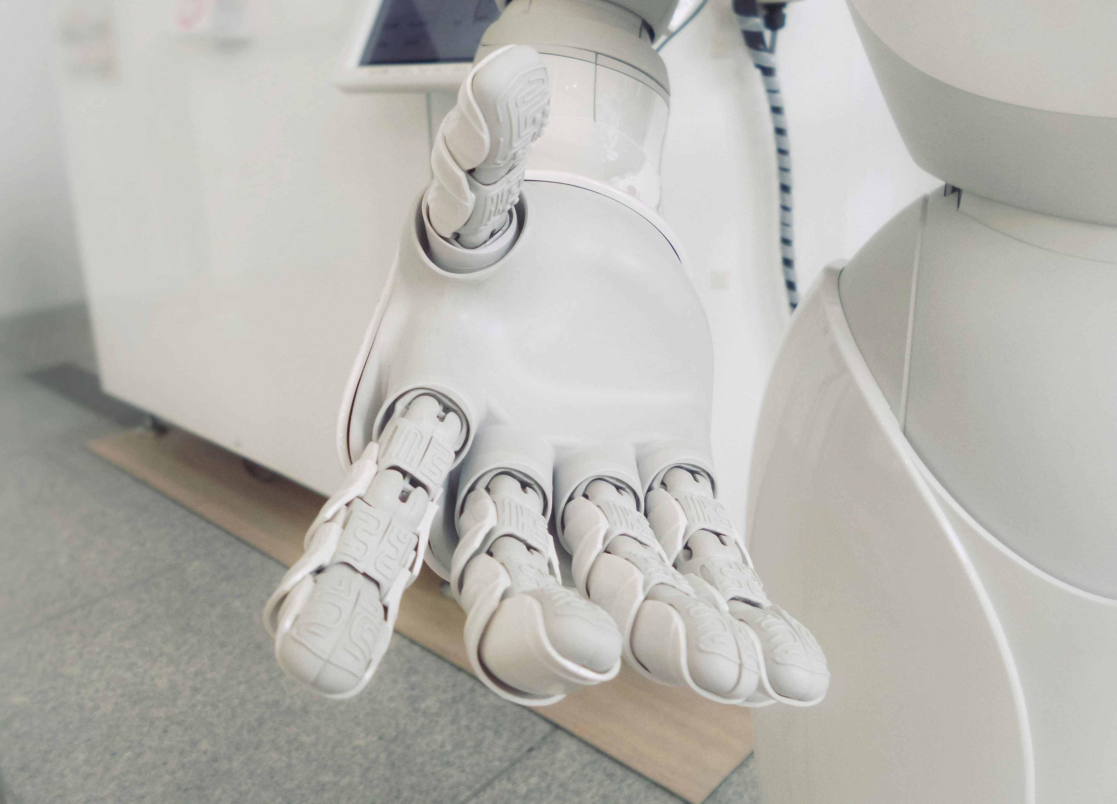Main d'un robot humanoïde blanc tendue vers l'avant, doigts articulés visibles