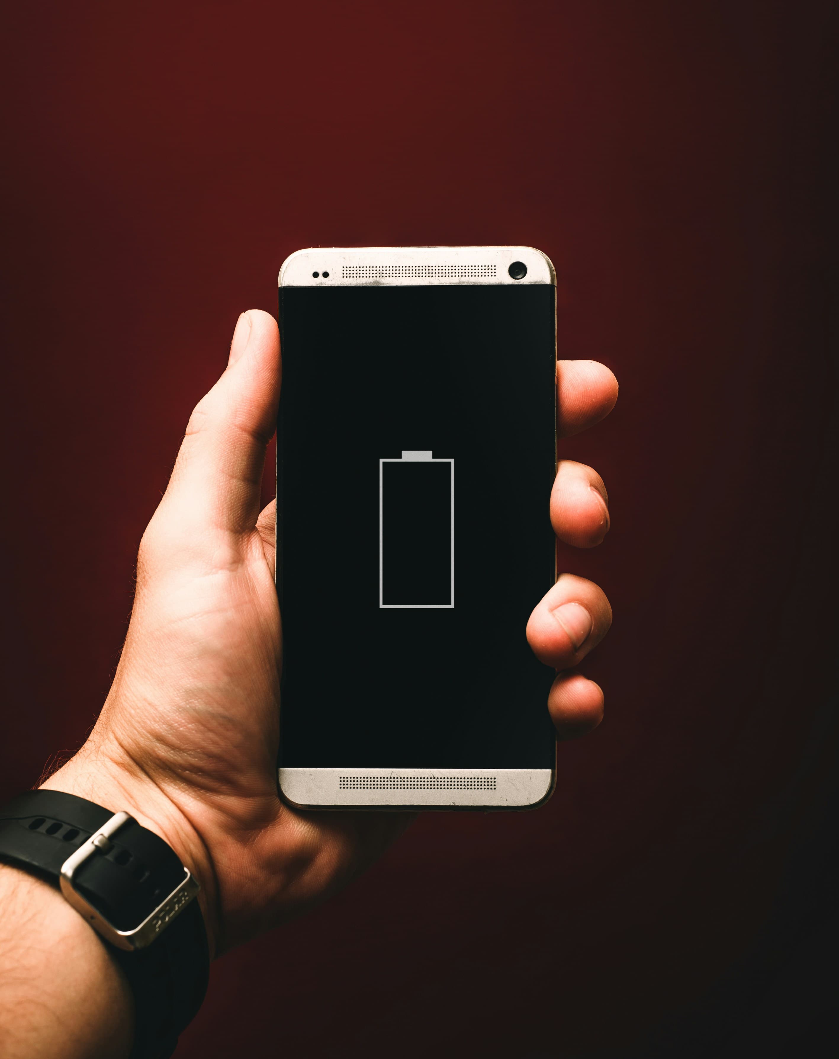 Personne tenant un smartphone affichant une batterie faible