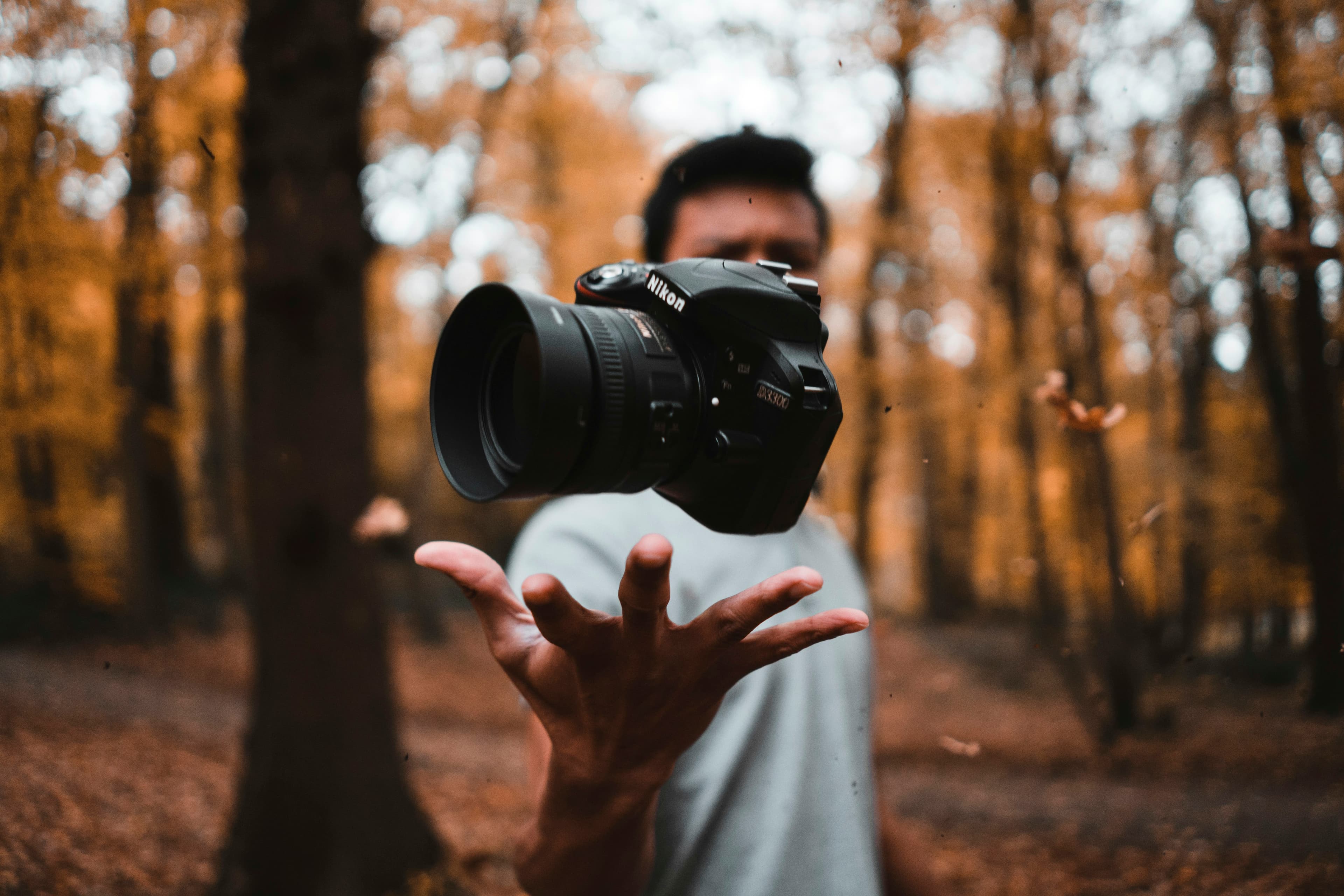 Appareil photo reflex numérique noir flottant au-dessus d'une main, en forêt