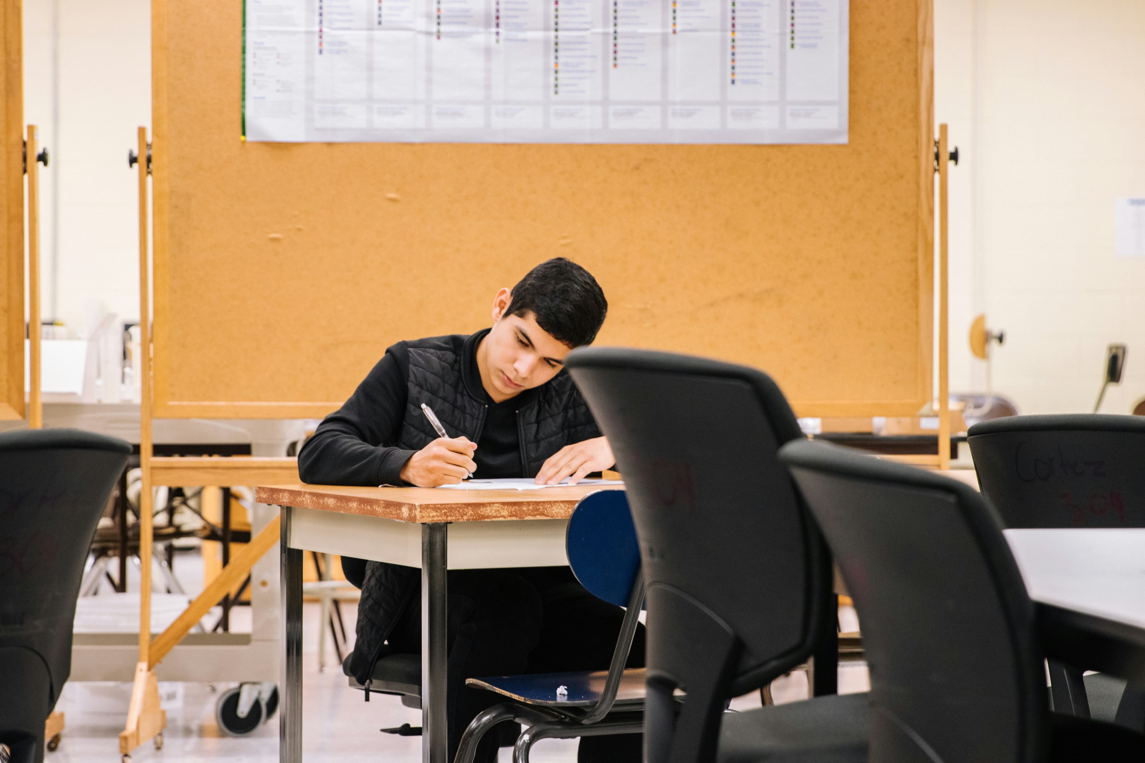 Personne assise à un bureau dans un contexte d'étude, visage non identifiable