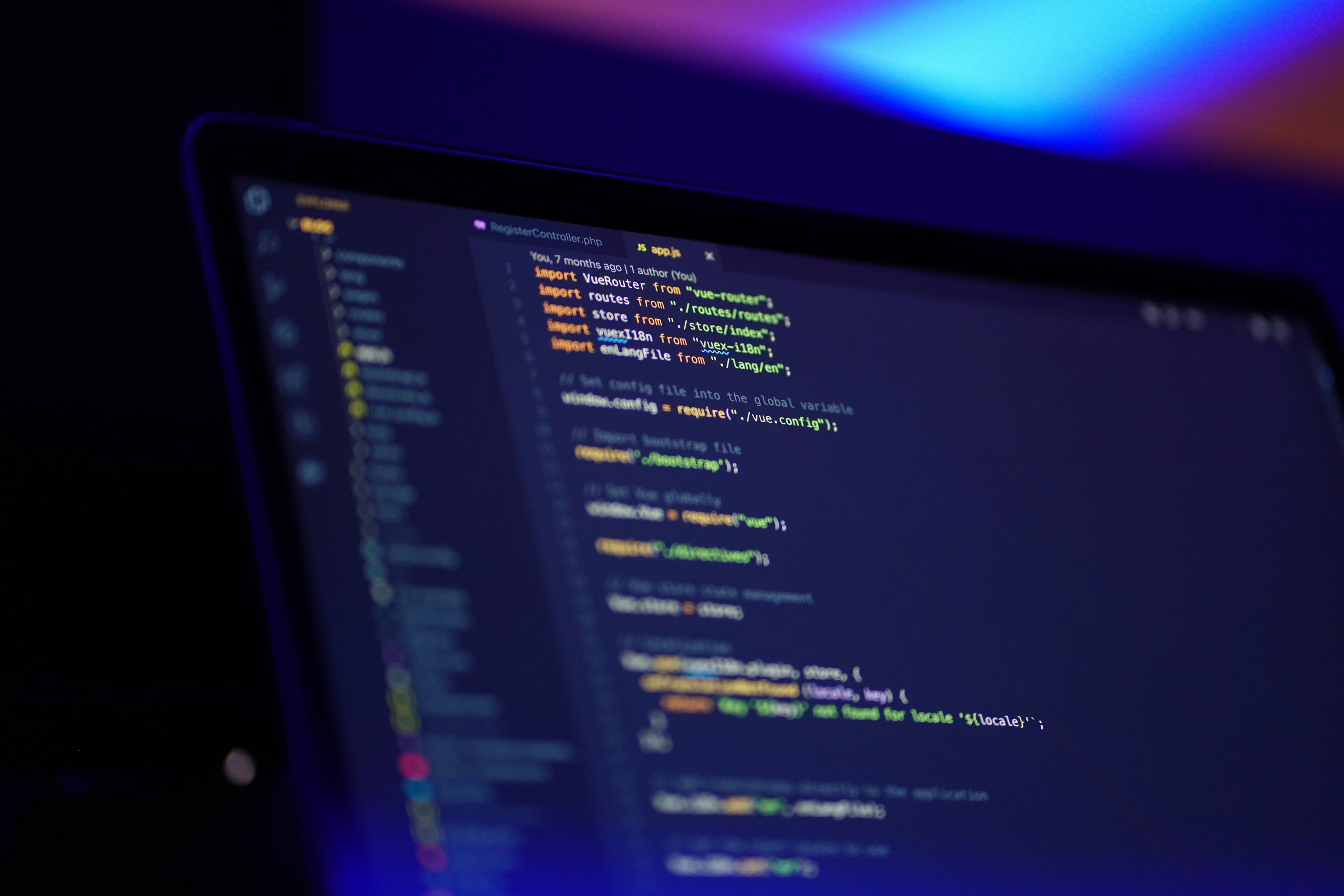 Un ordinateur portable ouvert dont l'écran affiche du code source coloré dans un éditeur sombre.
