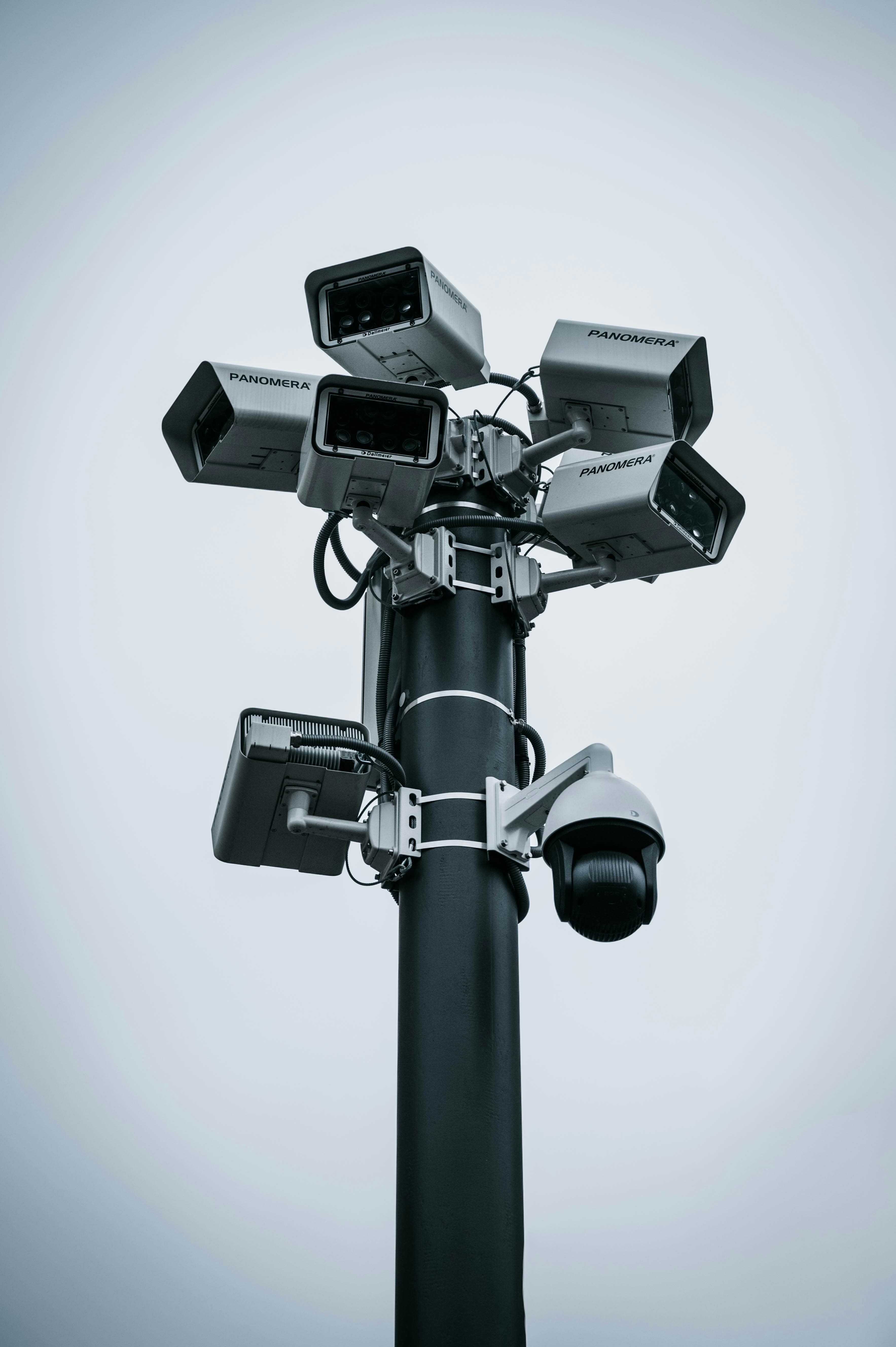 Un mât équipé de plusieurs caméras de vidéosurveillance sous un ciel gris