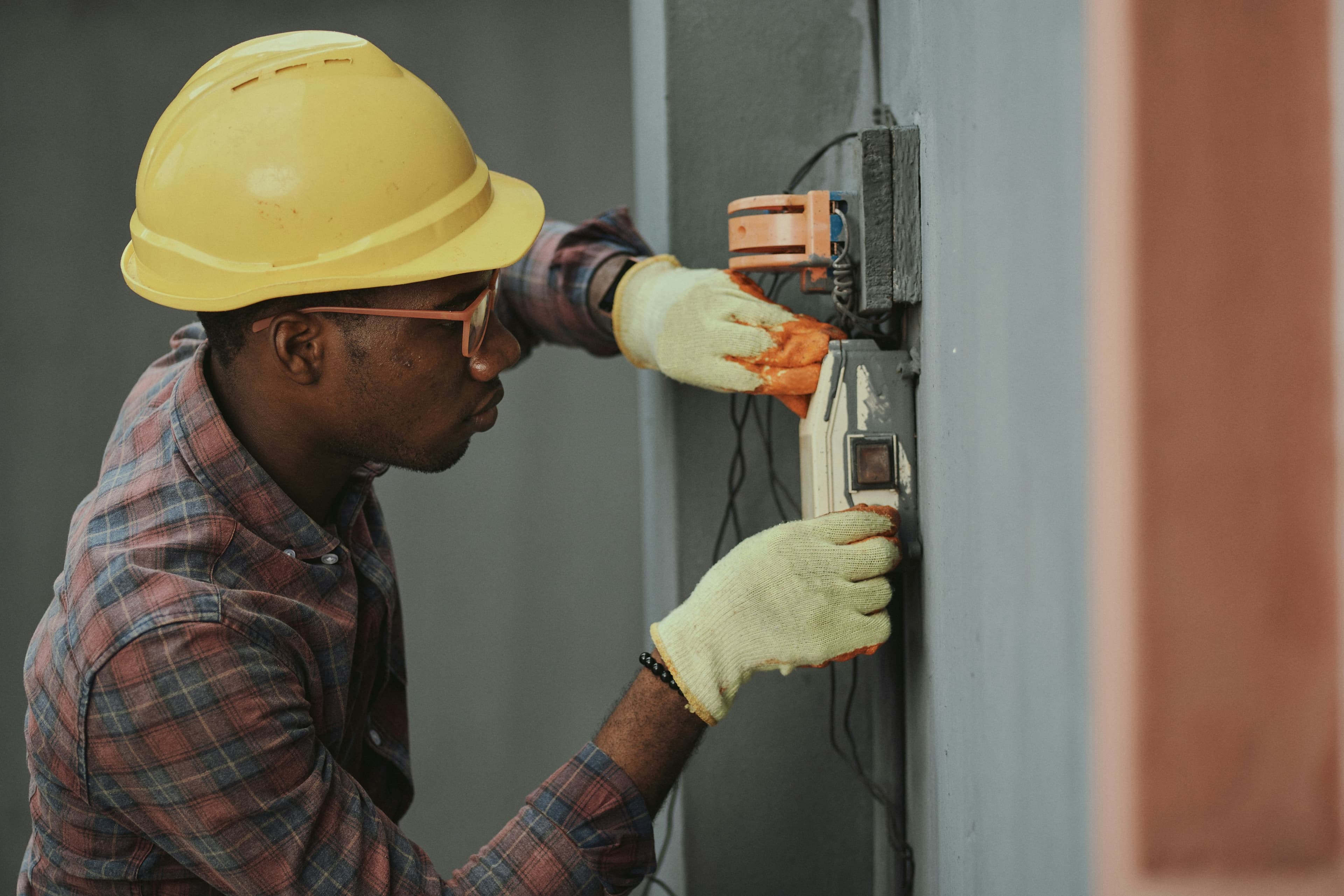 Un électricien installe un câblage, casque de chantier jaune sur la tête