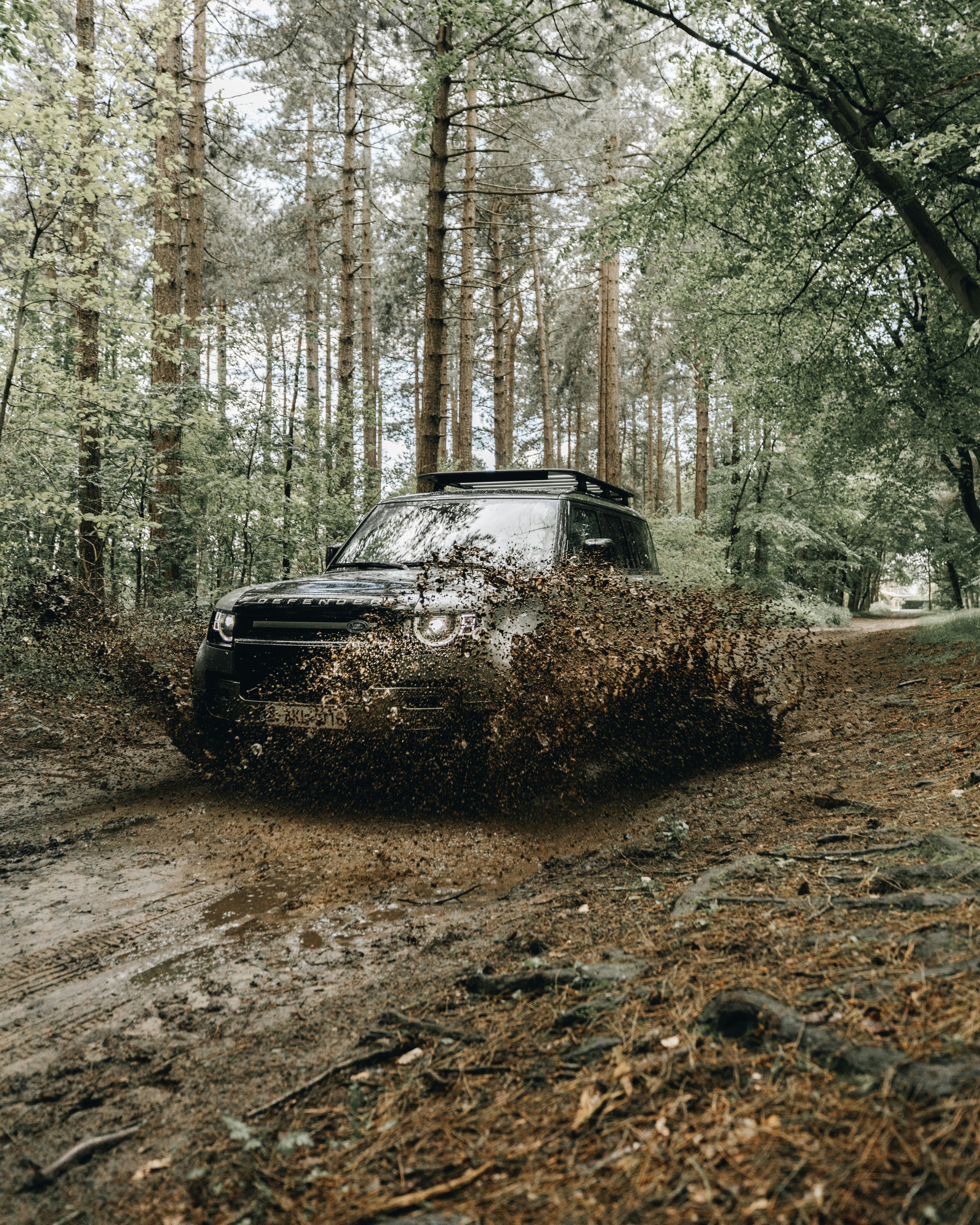 Voiture noire circulant sur un chemin de terre entre les arbres