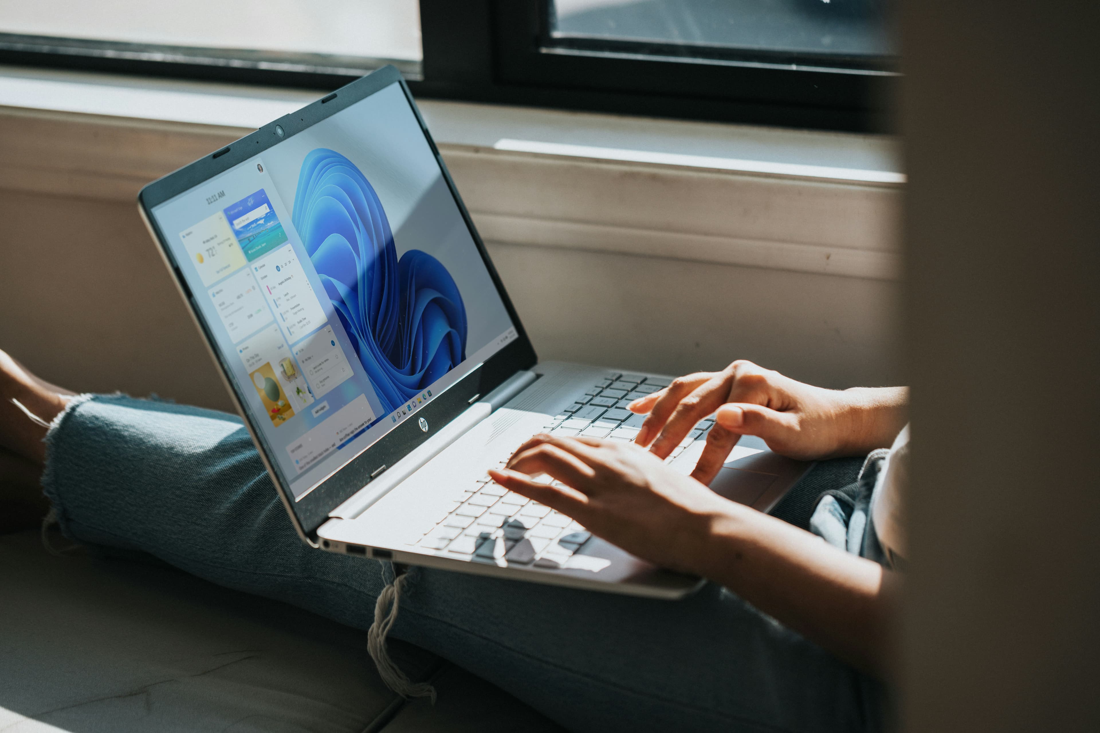 Personne travaillant sur un ordinateur portable sous Windows 11 posé sur ses genoux