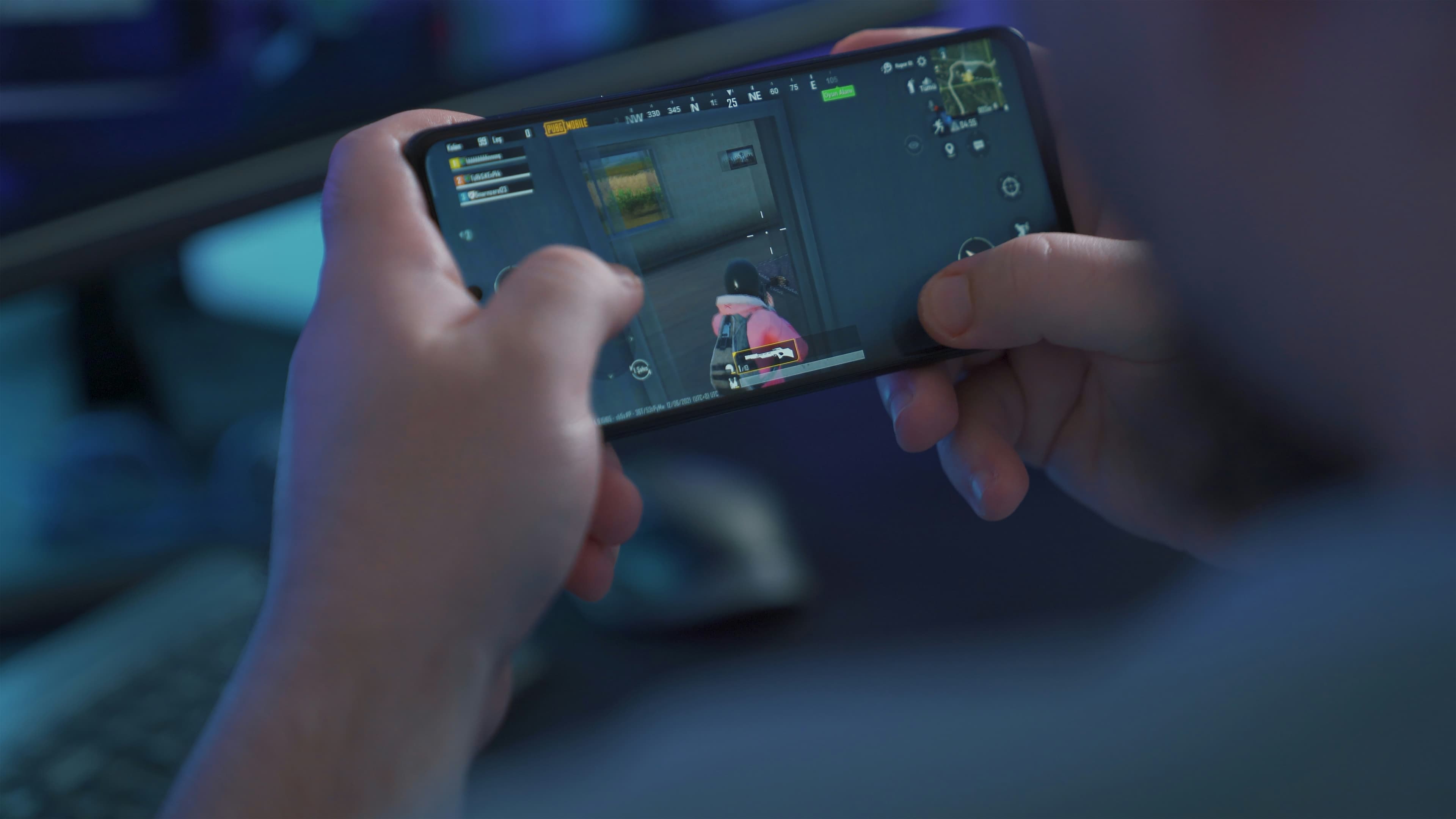 Main tenant un smartphone noir affichant un jeu mobile en vue à la première personne.