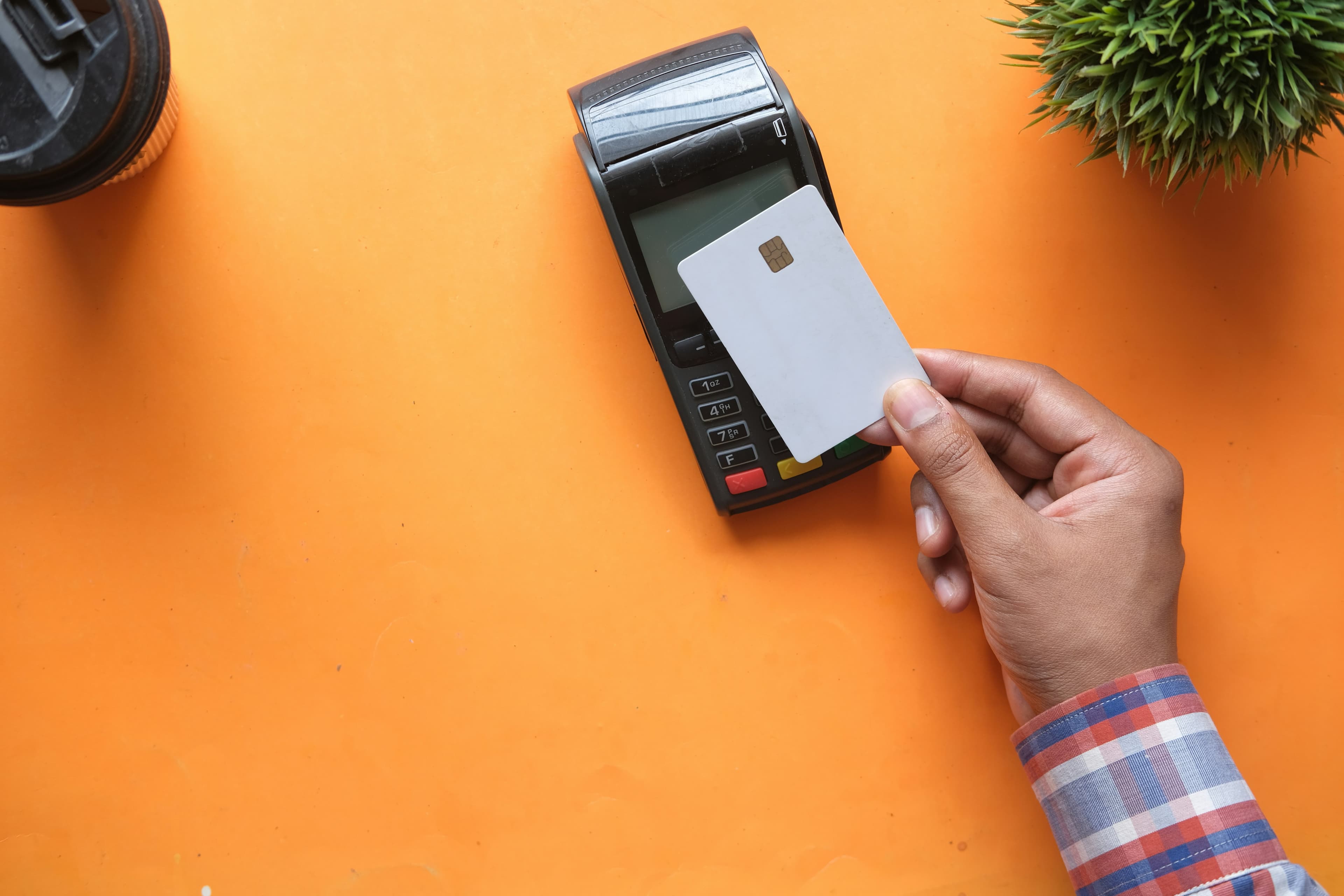 Personne tenant une carte de paiement vierge près d'un terminal de paiement