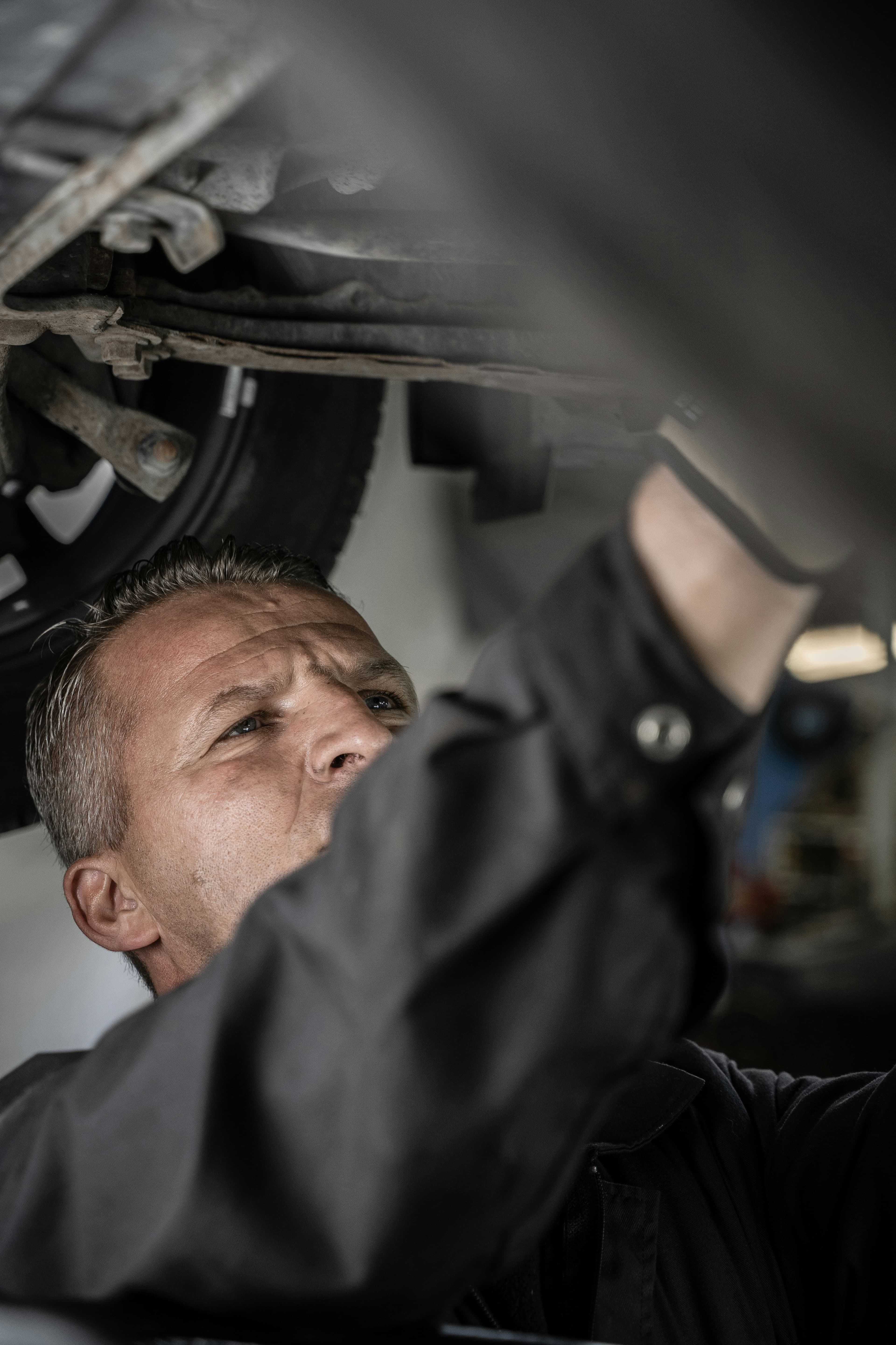 Un mécanicien travaillant sous un véhicule soulevé dans un garage