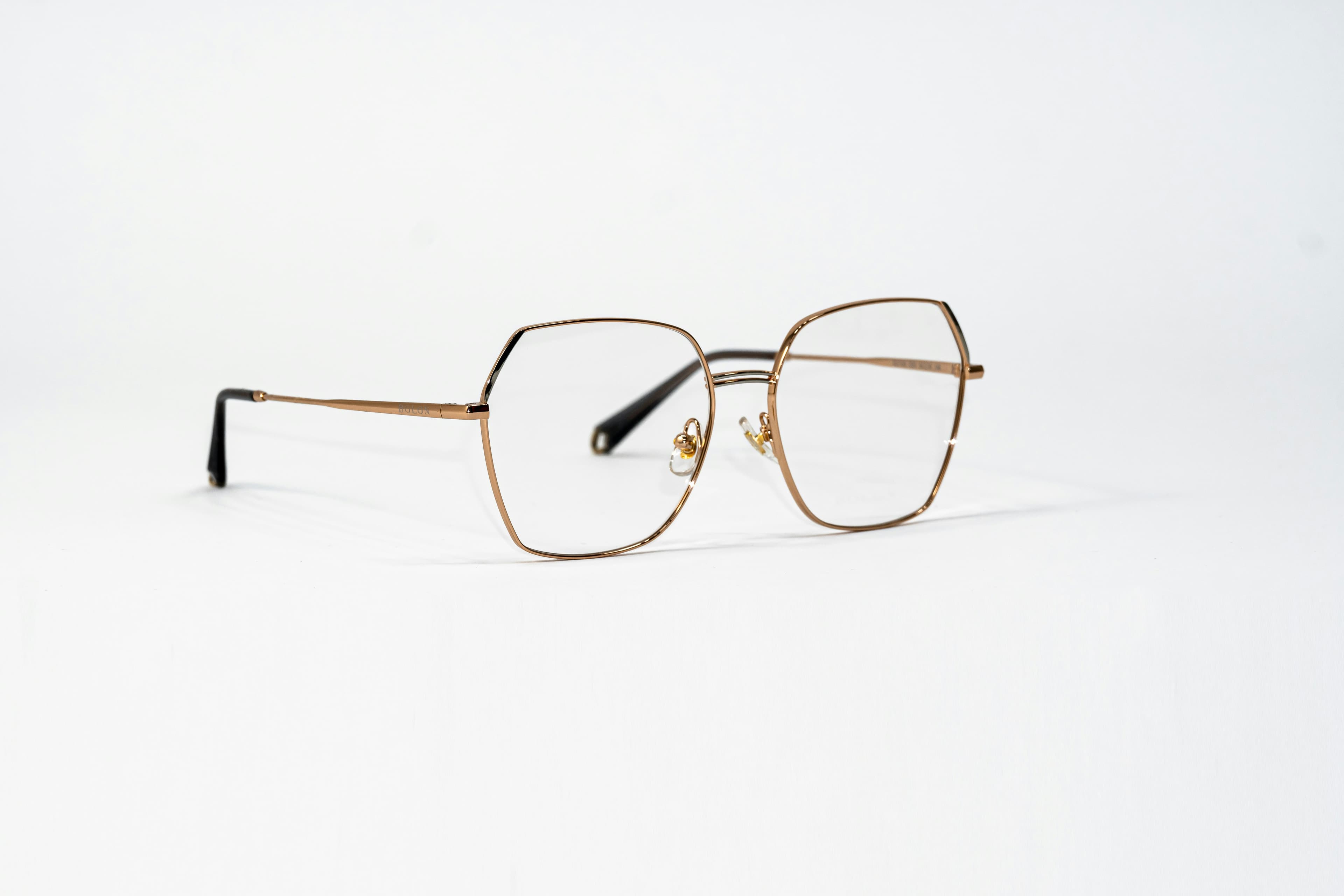 Une paire de lunettes à monture dorée posée sur une surface blanche
