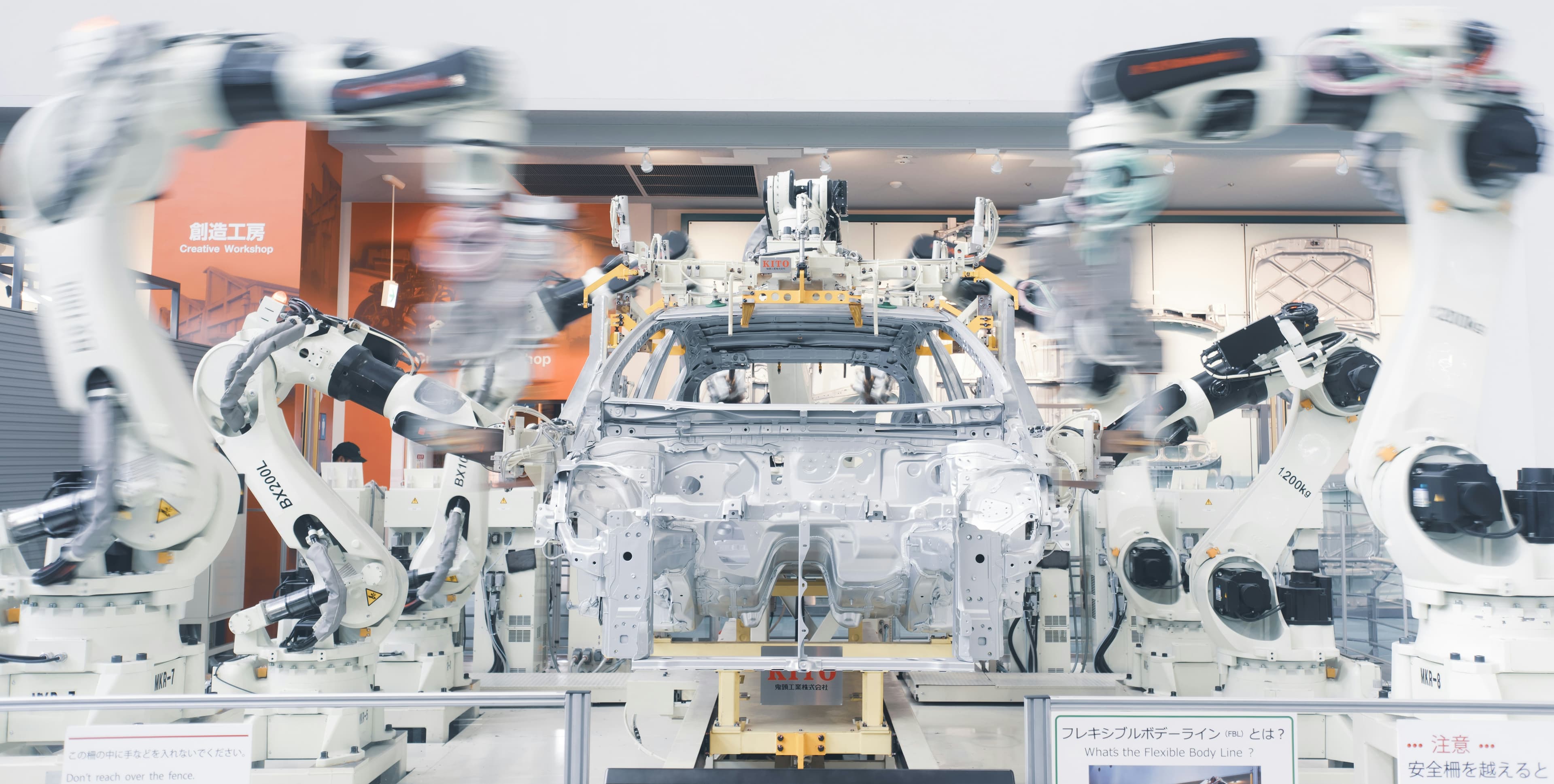 Bras robotisés assemblant un châssis de voiture sur une chaîne de production automobile