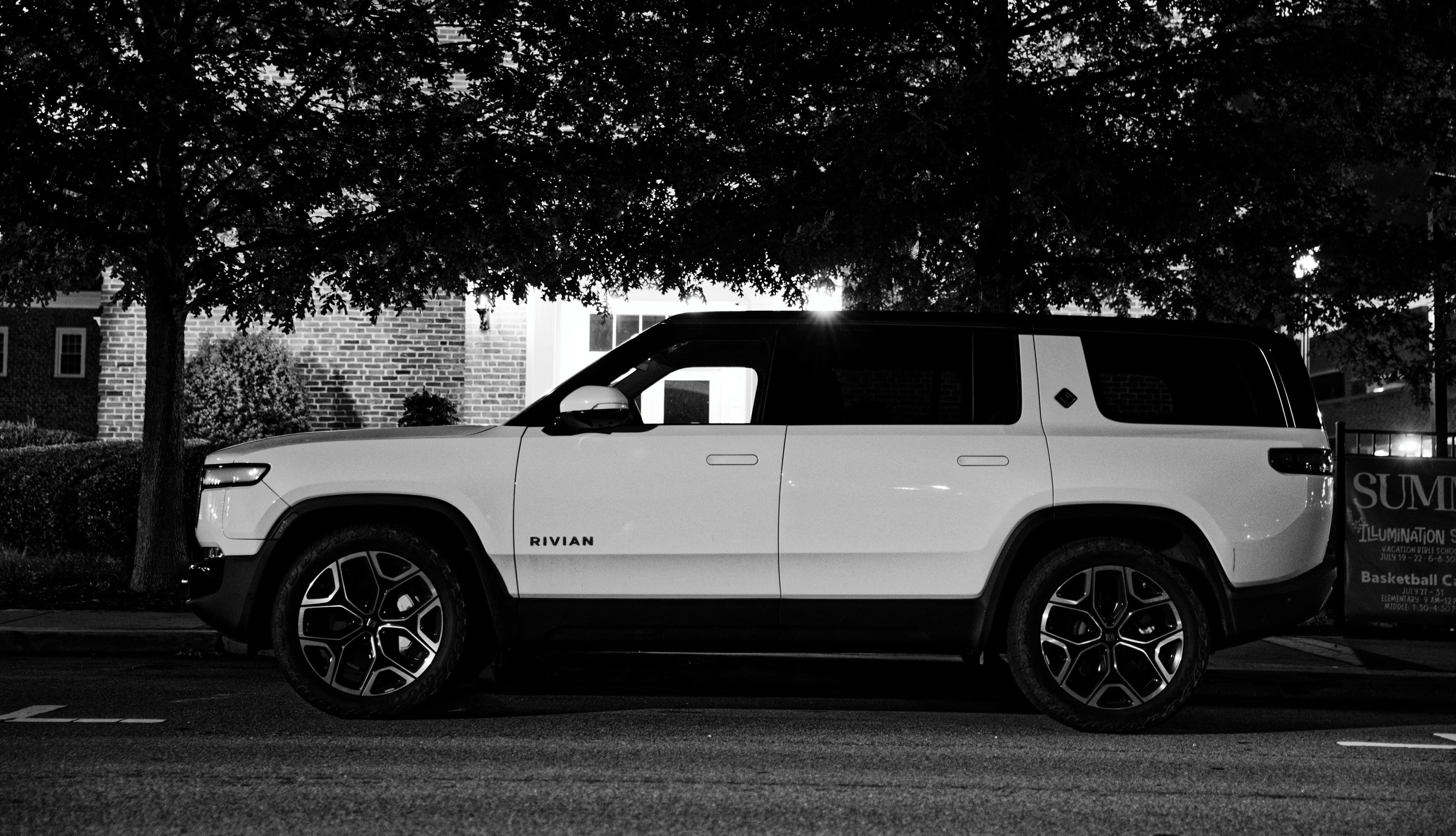 SUV blanc stationné sous des arbres de nuit