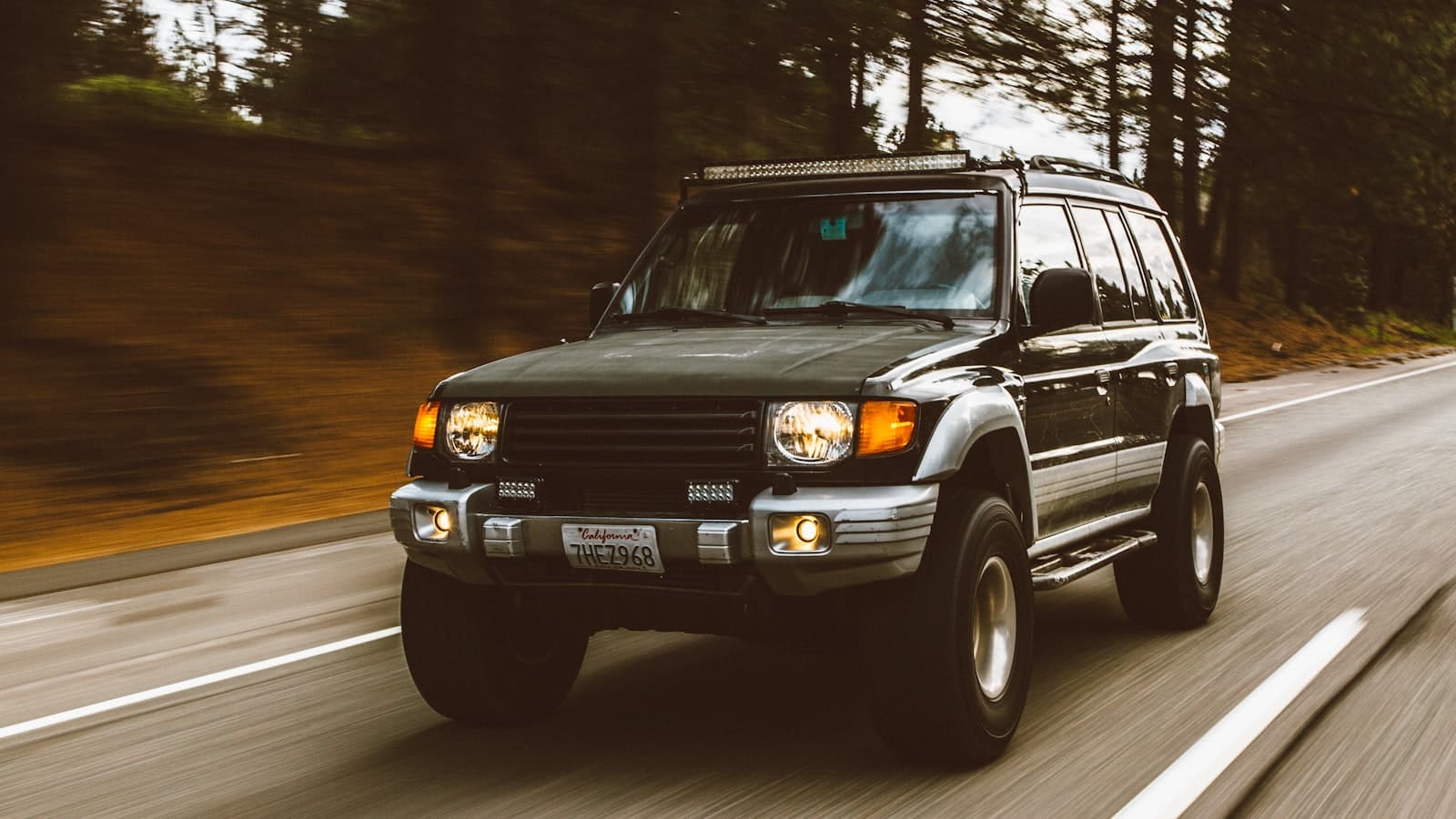 Un SUV vert en mouvement sur une route, filé photographique.